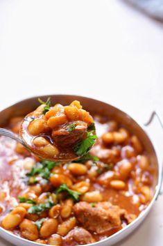 a spoon full of beans and meat with parsley