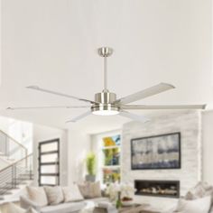 a ceiling fan in a living room with white walls and furniture around the fireplace area