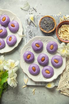 there are many purple donuts on the plate next to some flowers and other things