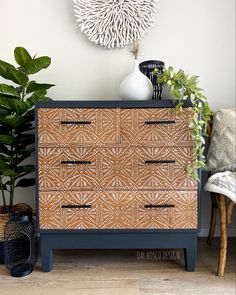 a brown and black dresser sitting next to a potted plant