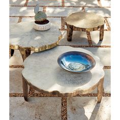 three wooden tables sitting next to each other on top of a stone floor with cactus in the background