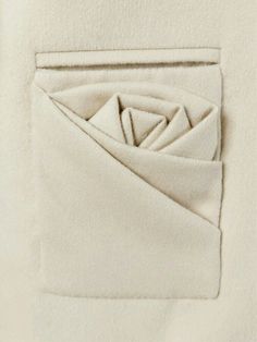 a white jacket with an origami design on the pocket