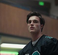 a young man in a black jersey holding a white frisbee