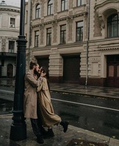 two people standing next to each other near a street light