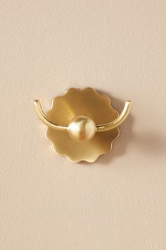 a gold door handle with a pearl in the center on a beige wall behind it