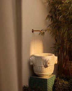 a planter sitting on top of a green box next to a wall mounted faucet