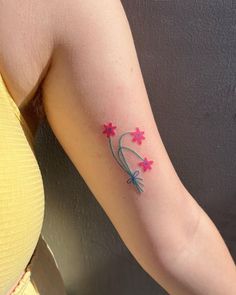 a woman's arm with pink flowers on it and a small blue flower in the middle