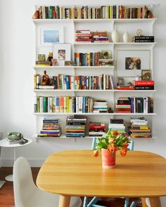 a wooden table topped with a potted plant next to a bookshelf filled with books