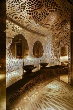 an artisticly designed bathroom with circular mirrors and lights on the walls, along with two sinks