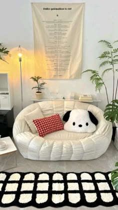 a white couch with a black and red pillow on top of it next to a potted plant