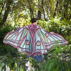 a woman holding a butterfly shaped umbrella in the woods