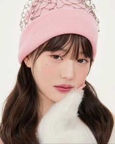 a young woman wearing a pink hat and white fur coat, posing for the camera