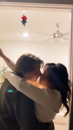 two women hugging each other in front of a window with christmas decorations hanging from the ceiling