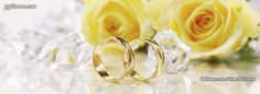 two wedding rings sitting next to yellow roses