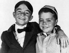 an old black and white photo of two young boys in tuxedos smiling at the camera