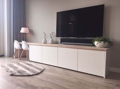 a flat screen tv sitting on top of a wooden entertainment center next to a window