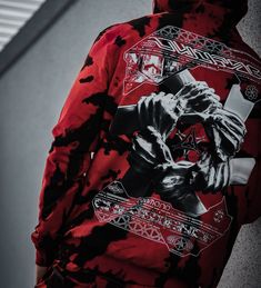 a man wearing a red and black hoodie with an image of a demon on it