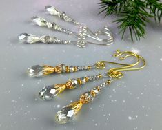 three pairs of gold and crystal earrings on top of a white table next to a christmas tree