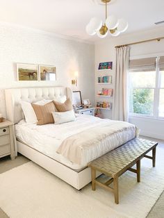 a white bed sitting in a bedroom on top of a wooden table next to a window