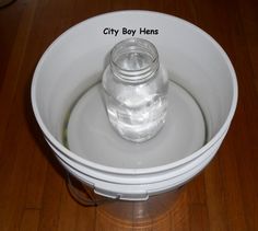 a glass jar sitting on top of a wooden table next to a white bowl filled with water