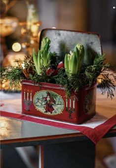 an old tin box with flowers in it on a table next to a christmas tree