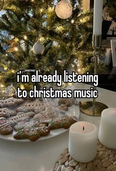 i'm already listening to christmas music with cookies and candles on the table next to it