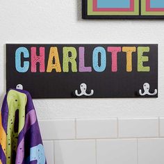 there is a sign that says charlotte on the wall next to a towel rack with hooks