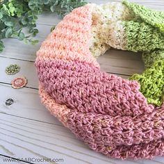 a crocheted scarf sitting on top of a wooden table next to a plant