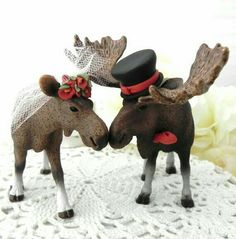 two moose figurines with hats and bows on their heads