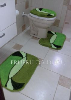 two green bathroom rugs in front of a toilet