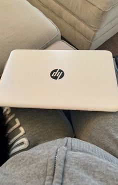 a laptop computer sitting on top of someone's lap in front of a couch