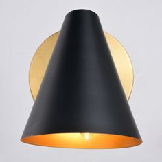 a black and gold wall light on a white wall with an orange light in the corner