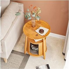 a small wooden table with flowers in a vase sitting on top of it next to a couch