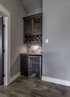 an empty kitchen with gray walls and wood flooring in the corner, along with a wine rack