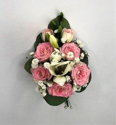 a bouquet of pink roses and white flowers on a gray background with greenery in the corner