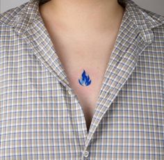 a woman with a blue flower tattoo on her left chest and right breast is wearing a checkered shirt