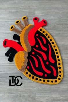 a heart shaped rug on top of a wooden floor with red and black designs in the middle