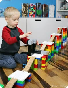 a young boy playing with lego blocks on the floor