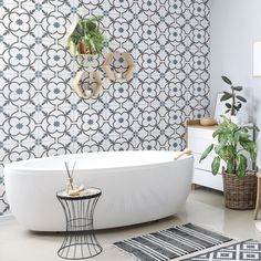 a white bath tub sitting in a bathroom next to a rug and potted plants