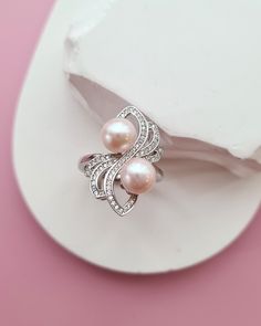 This stunning pearl ring features two luminous light pink freshwater pearl near the center, beautifully decorated by cubic zirconia floral petals. The unique, elegant design makes it a perfect statement piece for any occasion. Ideal for those who love a blend of classic pearls and modern sparkle, this ring adds a touch of sophistication and charm to any look. ♡ Freshwater Pearl Rings FWPR_24_S_1 ♡  ✧ Pearl size: Approx 7.6mm. ✧ Pearl Color: Very light pink. As shown in the pictures/video. ✧ Surface: High lustre, smooth surface. You can view from our pictures / video for close up. ✧ 18k White gold vermeil (925 Sterling silver base) setting. ✧ Cubic zirconia. ✧ Ring size: Adjustable (If you want me to adjust the size for you before shipping out, please let me know your US ring size at check Tahitian Pearls Jewelry, Silver Pearl Jewelry, Pearl Rings, Freshwater Pearl Jewelry, Freshwater Pearl Ring, Jewelry Minimalist, Pink Ring, Pink Pearl, Pearl Color