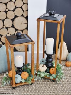 two wooden lanterns sitting next to each other on top of a floor covered in leaves and pumpkins