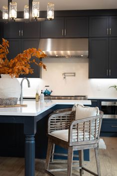 a kitchen with black cabinets and white countertops has a bar stool that matches the wooden flooring