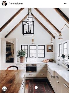 a kitchen with white walls and wooden beams on the ceiling is decorated with potted plants