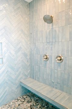 a white tiled shower with two silver faucets and a bench in the corner