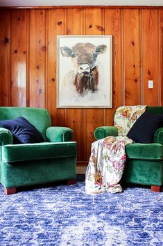 two green chairs sitting next to each other in front of a painting on the wall