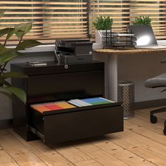 an office desk with a printer, file cabinet and chair in front of the window