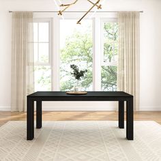 a black table in front of two windows and a rug on the floor with a plant