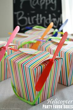 colorful striped boxes with toothbrushes sticking out of them on a table in front of a happy birthday sign