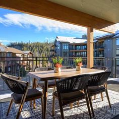 a wooden table sitting on top of a patio next to a balcony with mountains in the background