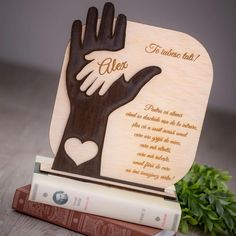 a wooden bookend with a hand holding a heart on top of two books next to each other